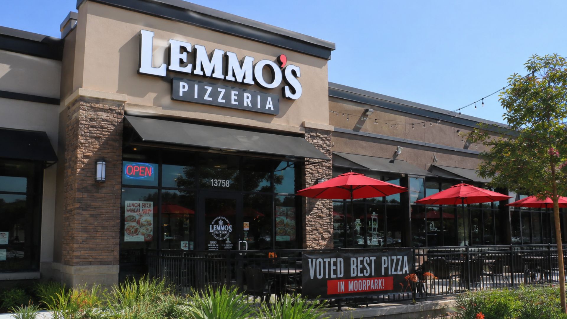 Front of Lemmo's Pizzeria storefront with stone façade, large LEMMO'S sign, outdoor seating under red umbrellas, and a banner reading 'Voted Best Pizza in Moorpark'.
